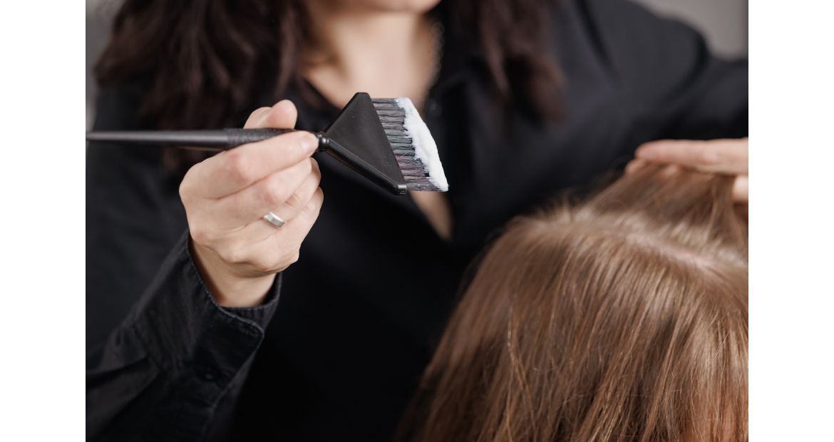 Profissional aplica tinta de cabelo para clarear os fios de sua cliente